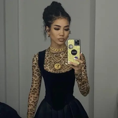 Jhené Aiko in a black outfit taking a selfie.